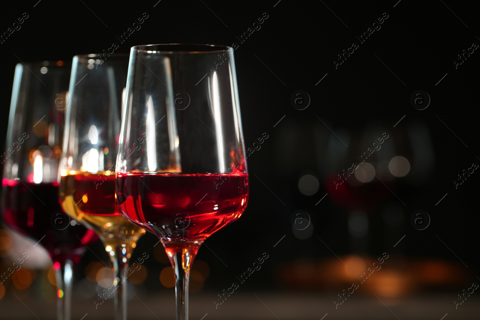 Photo of Row of glasses with different wines against blurred background, closeup. Space for text