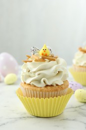 Photo of Tasty Easter cupcake with vanilla cream on white marble table, space for text