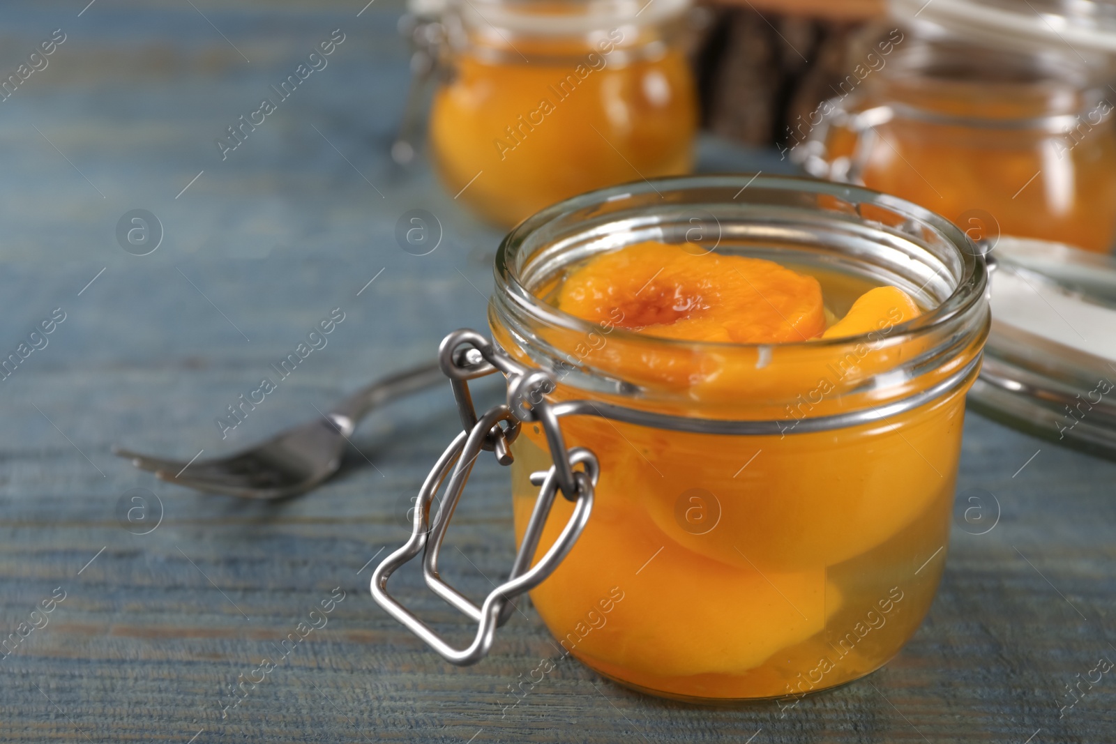 Photo of Glass jar with conserved peach halves on wooden table. Space for text