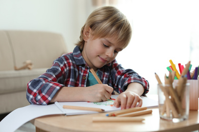 Photo of Little boy drawing at table indoors. Creative hobby