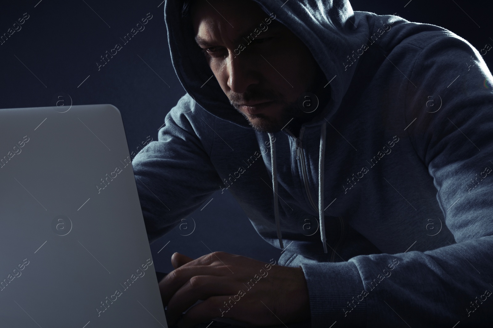 Photo of Man using laptop on dark background. Criminal activity