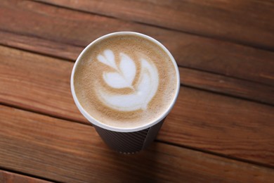 Photo of Coffee to go. Paper cup with tasty drink on wooden table, above view