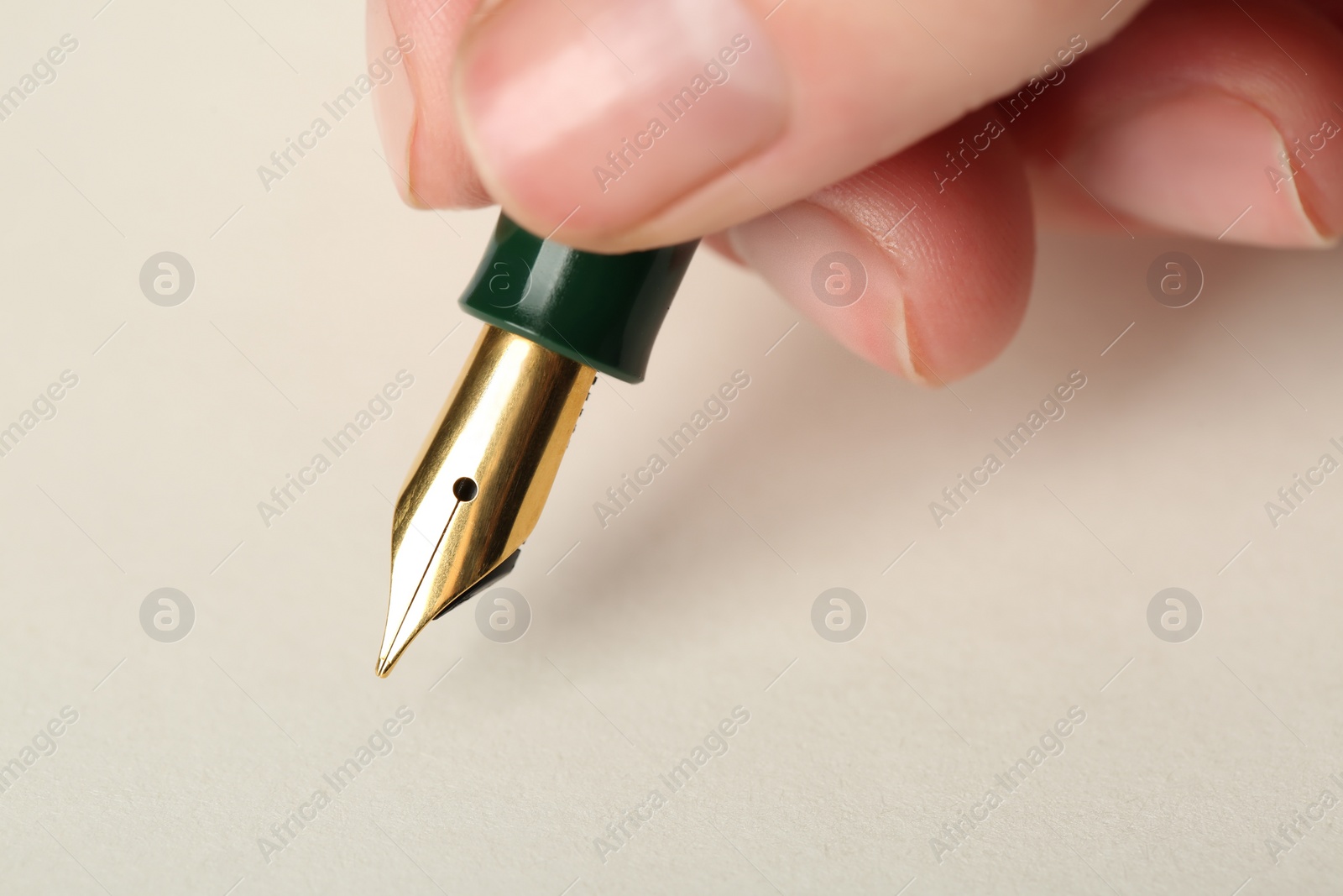 Photo of Woman with fountain pen above light paper, closeup