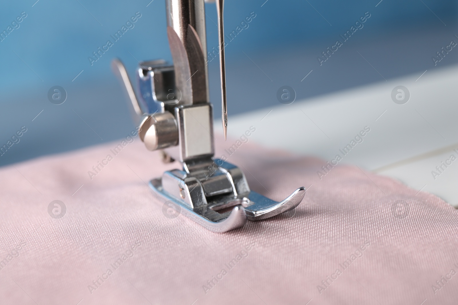 Photo of Sewing machine with color fabric on light background, closeup