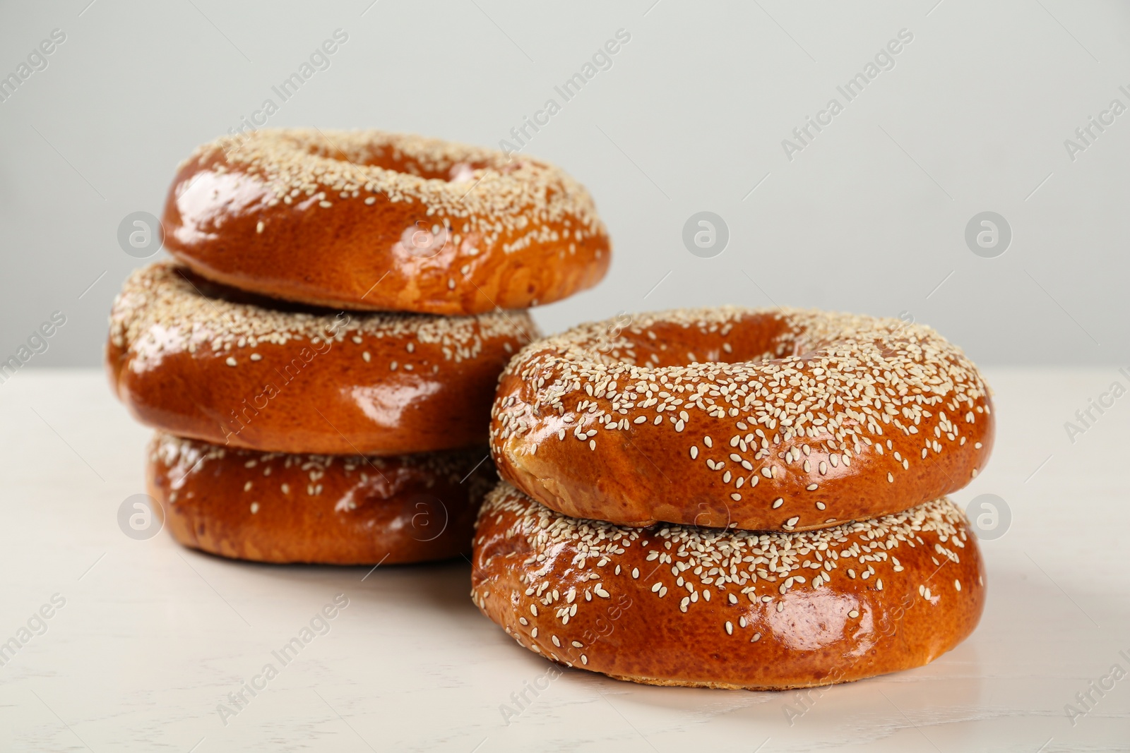 Photo of Delicious fresh bagels with sesame seeds on white wooden table