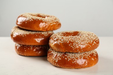 Photo of Delicious fresh bagels with sesame seeds on white wooden table