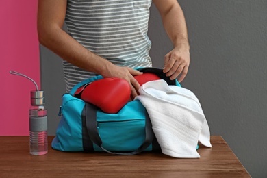 Photo of Young man packing sports bag on table