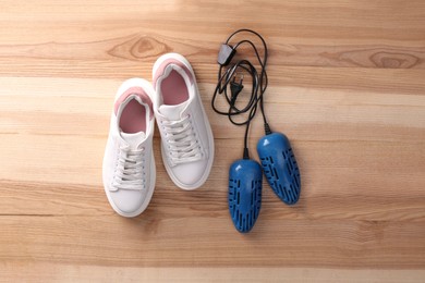 Shoes and electric dryer on wooden background, flat lay