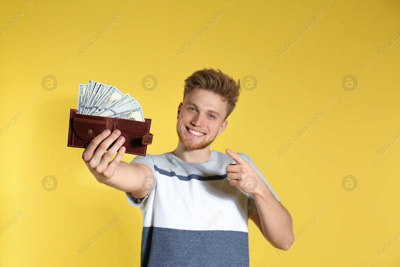 Photo of Young man with money in wallet on color background. Space for text