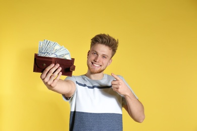 Young man with money in wallet on color background. Space for text