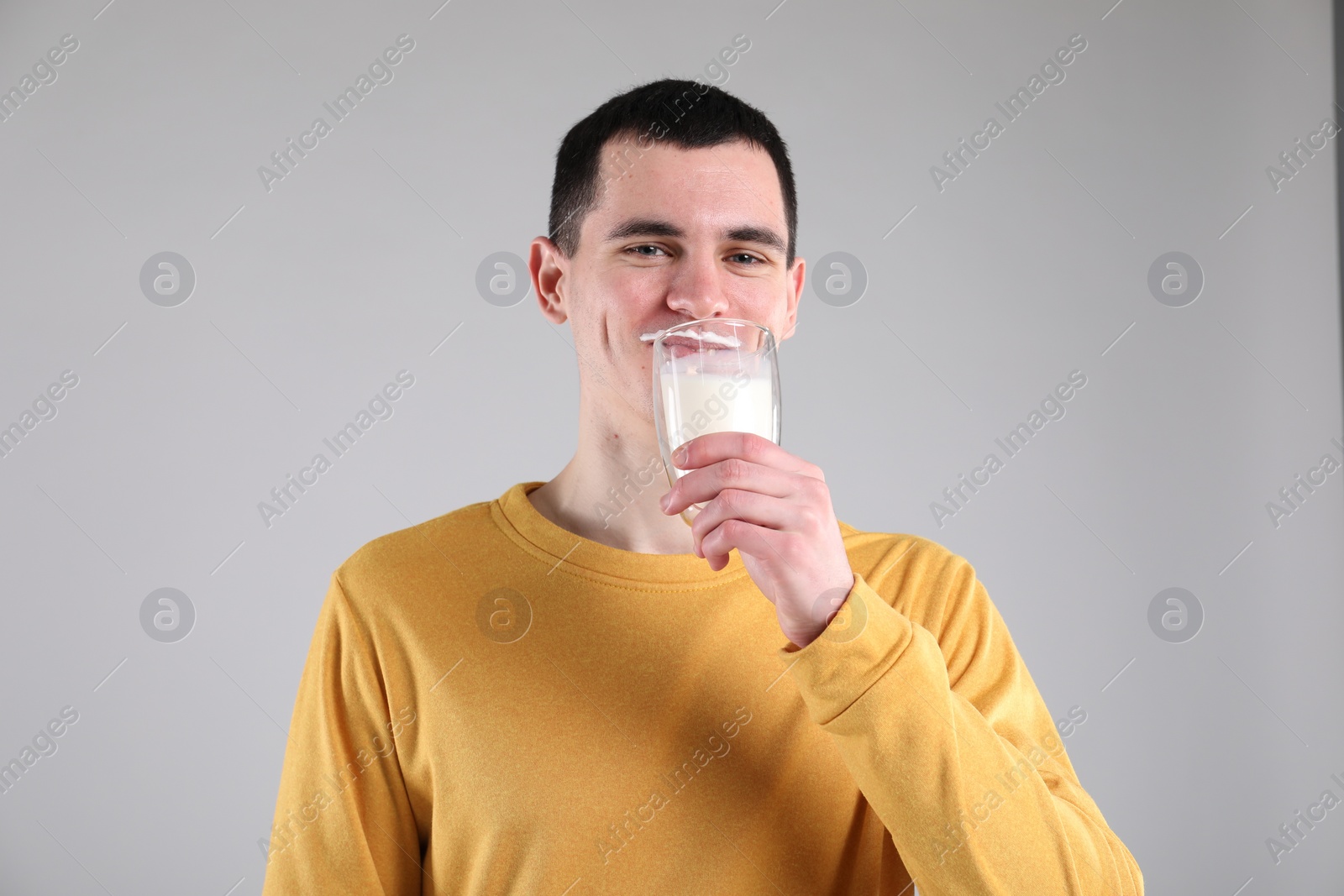 Photo of Milk mustache left after dairy product. Man drinking milk on gray background