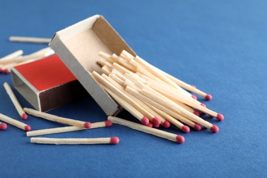 Photo of Open box and scattered matches on color background