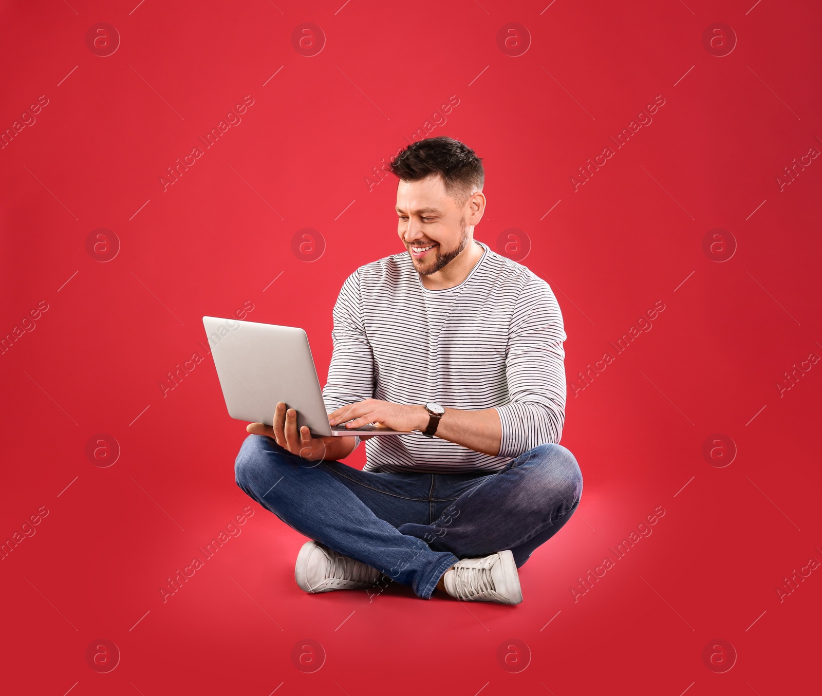 Image of Happy man with laptop on red background