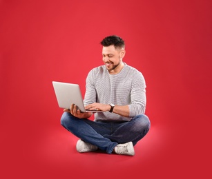 Happy man with laptop on red background