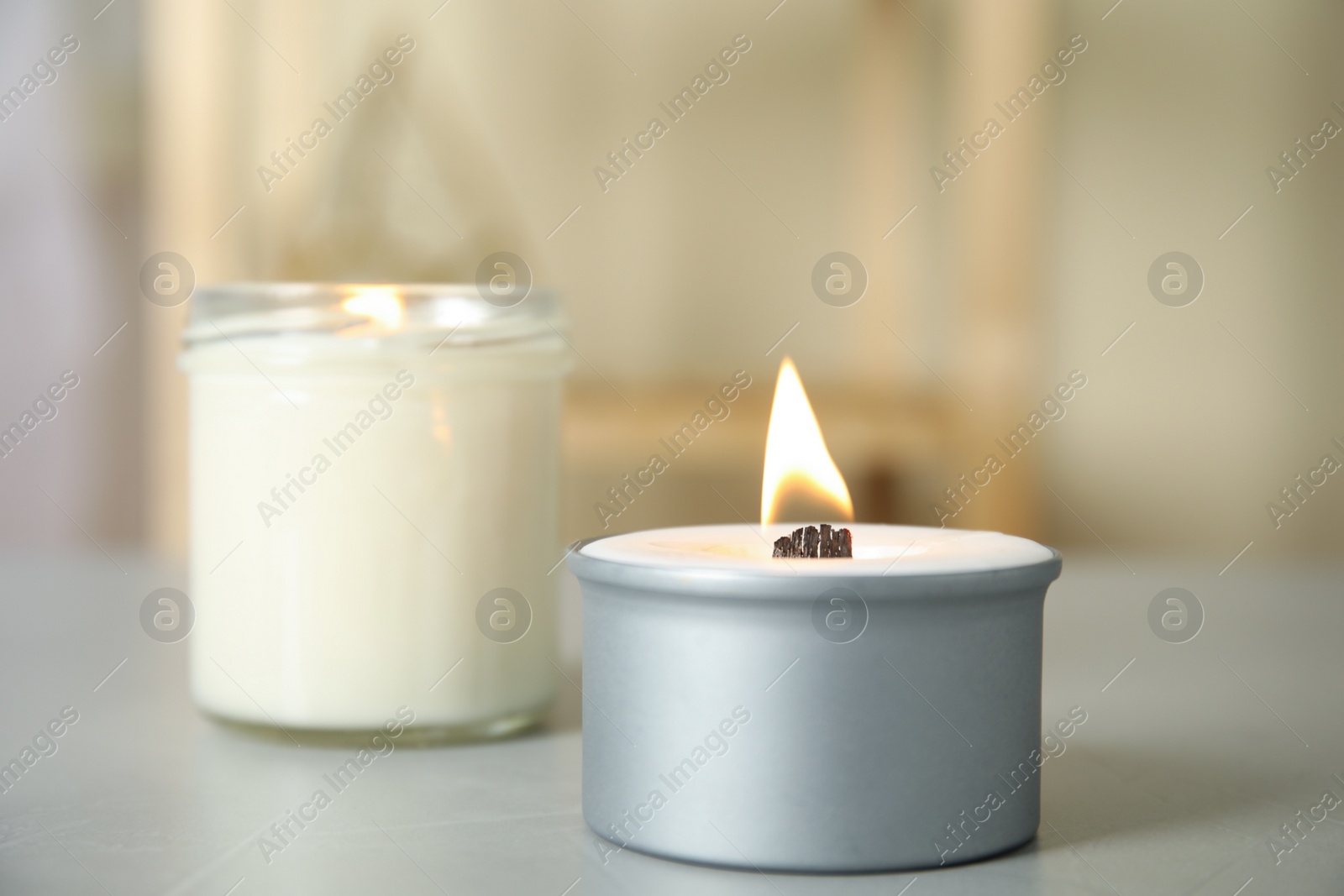 Photo of Burning candles in holders on light grey table