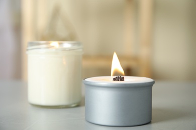 Photo of Burning candles in holders on light grey table