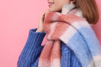 Photo of Woman in warm scarf on pink background, closeup. Space for text