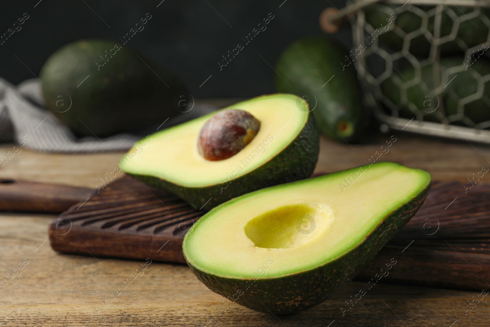 Photo of Halves of delicious ripe avocado on wooden table