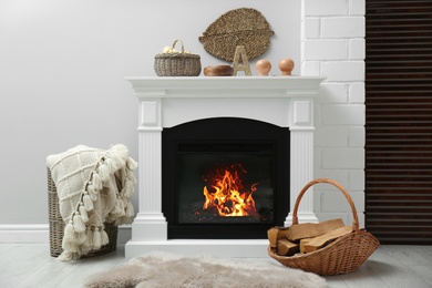 Photo of Wicker basket with firewood and white fireplace in cozy living room
