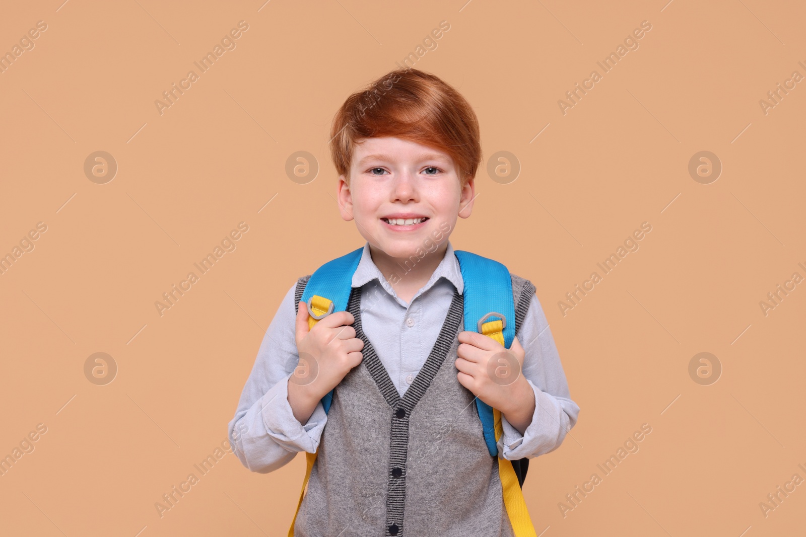 Photo of Portrait of smiling schoolboy on beige background
