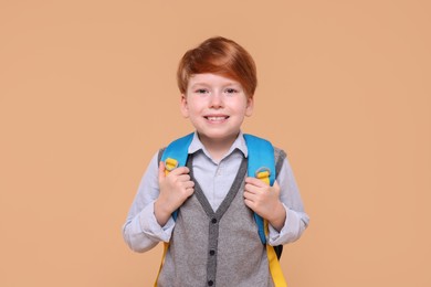 Portrait of smiling schoolboy on beige background