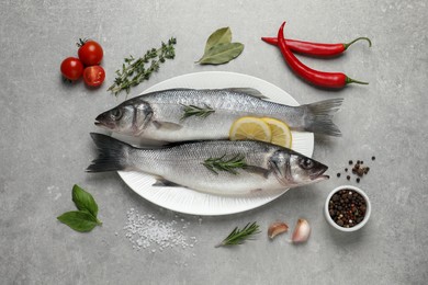 Photo of Sea bass fish and ingredients on grey table, flat lay