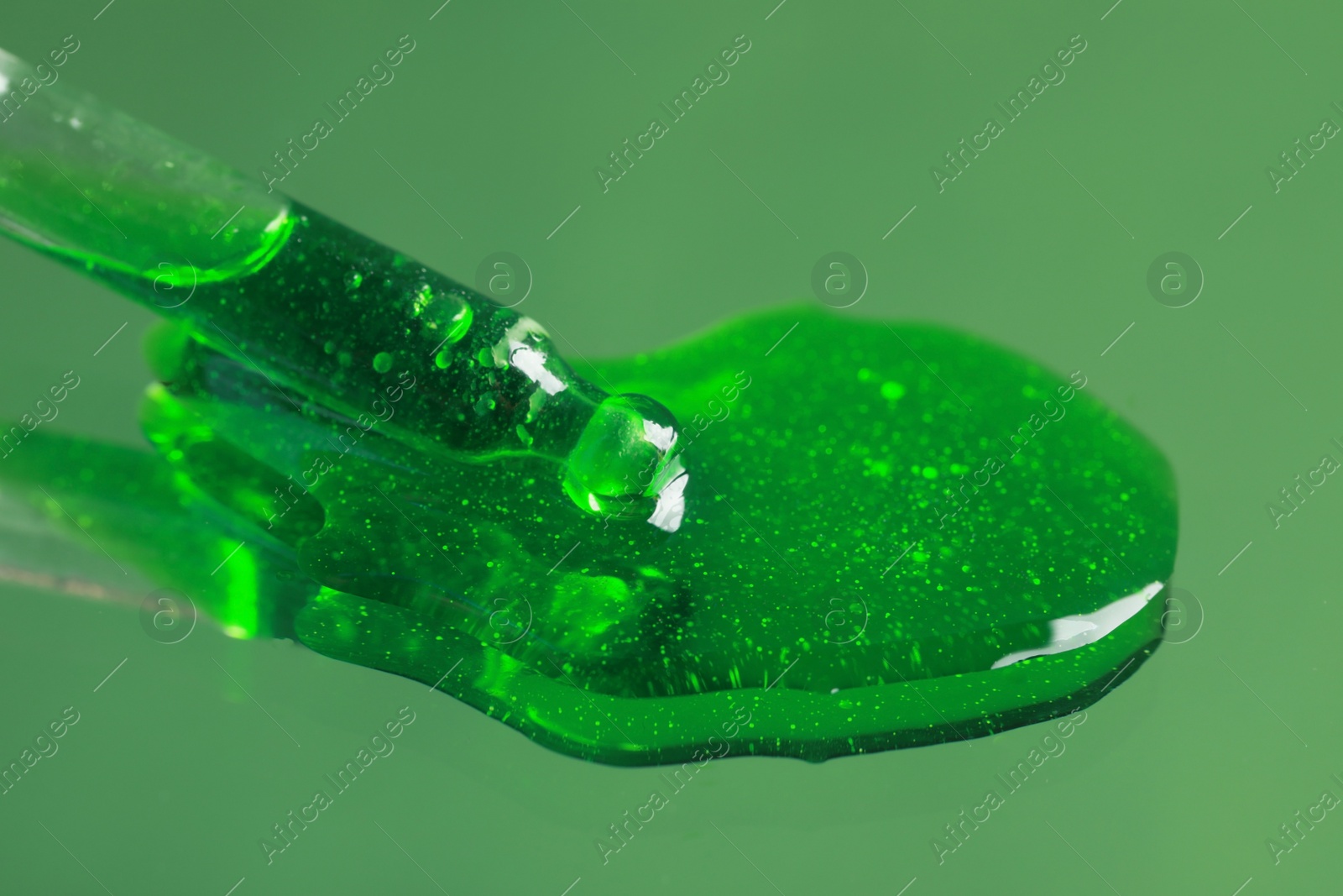 Photo of Dripping serum from pipette on mirror, closeup. Toned in green