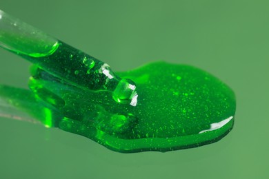 Photo of Dripping serum from pipette on mirror, closeup. Toned in green