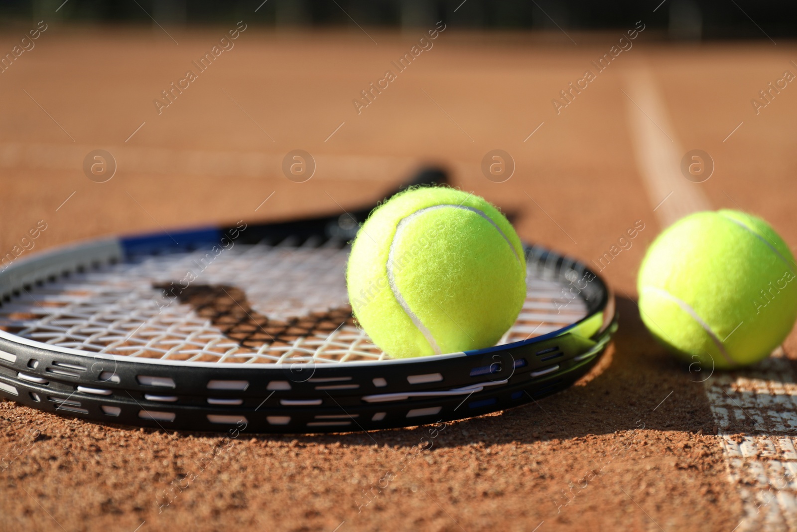 Photo of Tennis balls and racket on clay court, closeup