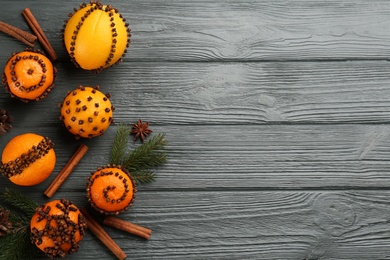 Flat lay composition with pomander balls made of fresh tangerines, orange and cloves on wooden table, space for text