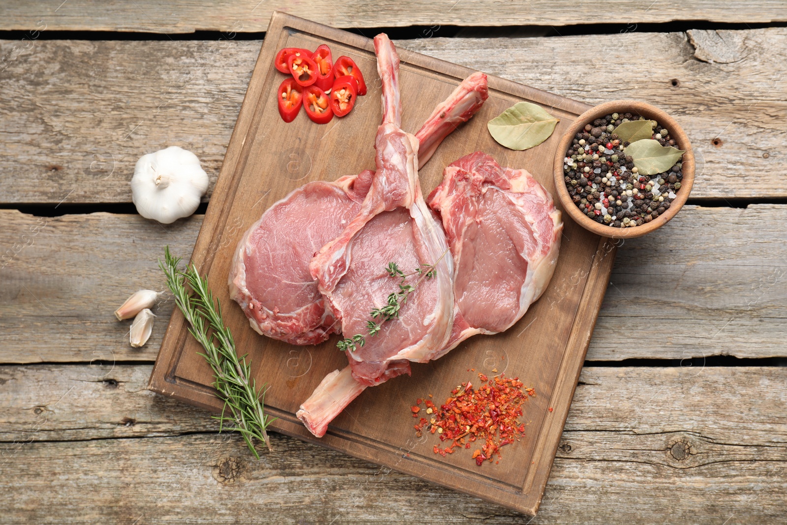 Photo of Fresh tomahawk beef cuts and spices on wooden table, top view