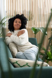 Woman relaxing on sofa near beautiful houseplants at home