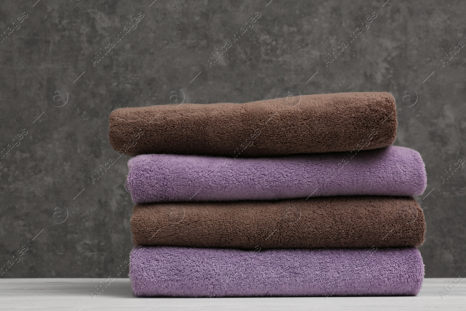 Photo of Stack of soft clean towels on table against color background