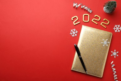 Photo of Golden planner and Christmas decor on red background, flat lay with space for text. Planning for 2022 New Year