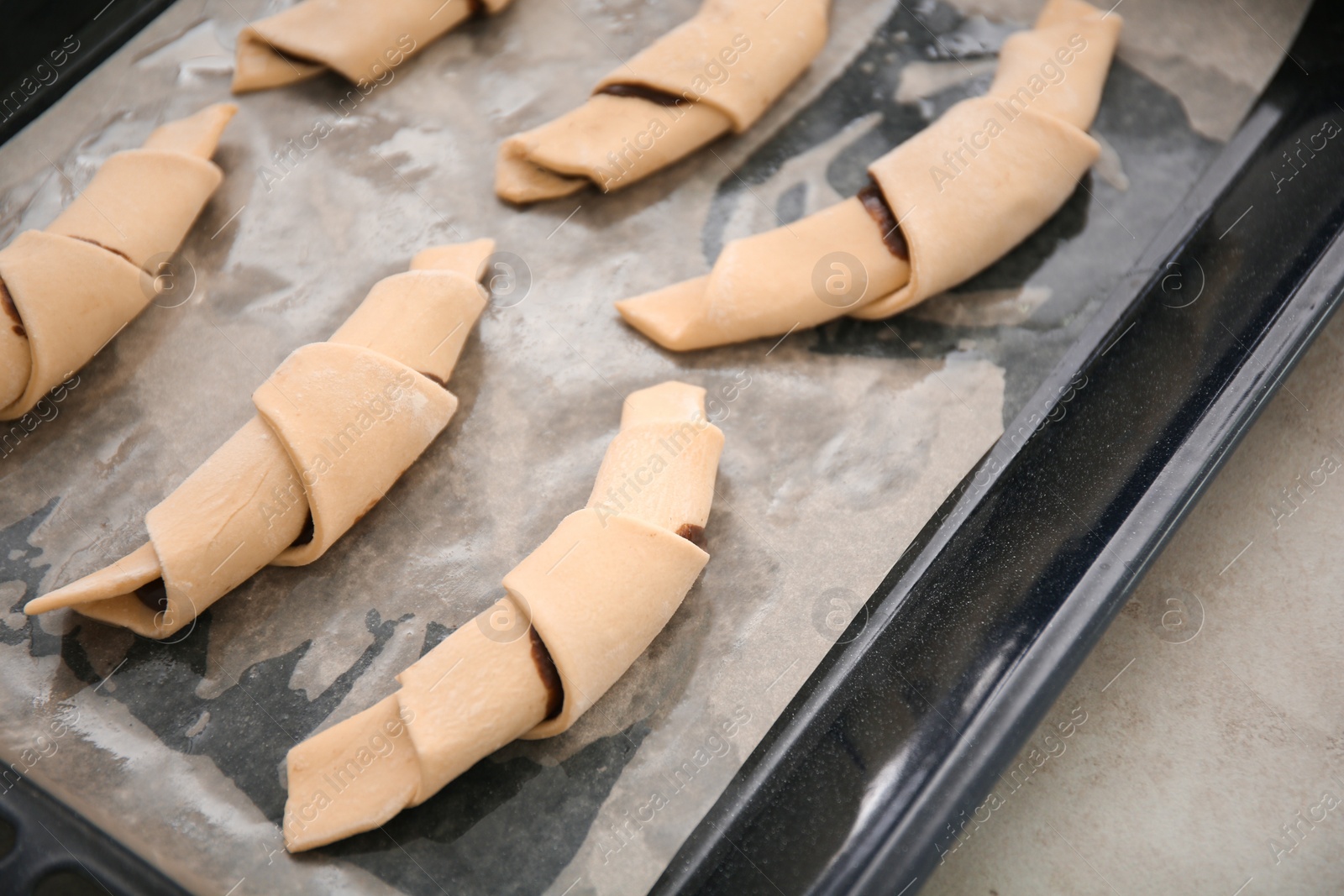 Photo of Baking sheet with raw croissants, closeup