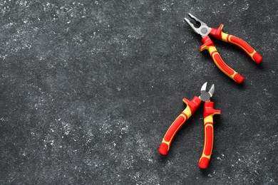 Pliers on black textured table, flat lay. Space for text