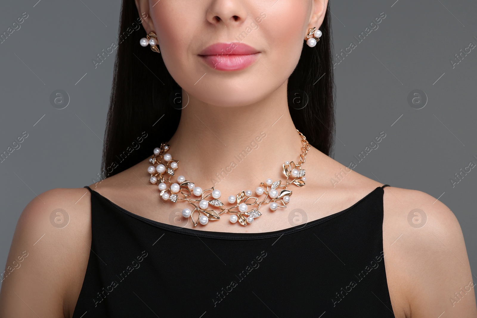 Photo of Young woman with elegant jewelry on dark grey background, closeup