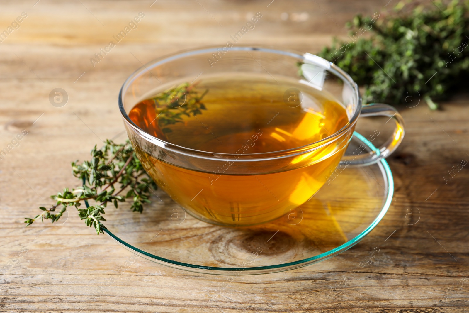 Photo of Aromatic herbal tea with thyme on wooden table
