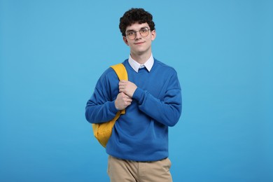 Portrait of student with backpack on light blue background