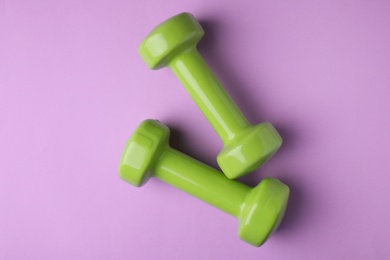 Photo of Bright dumbbells on color background, flat lay. Home fitness