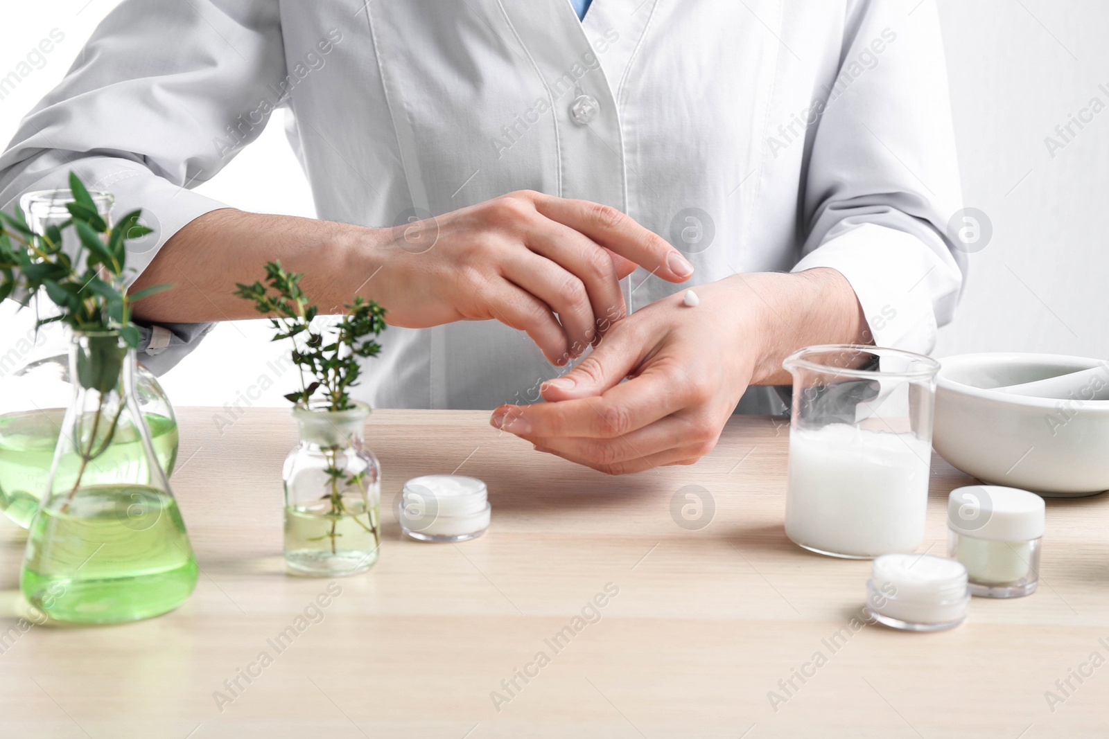 Photo of Woman applying natural cream onto hand in cosmetic laboratory, closeup