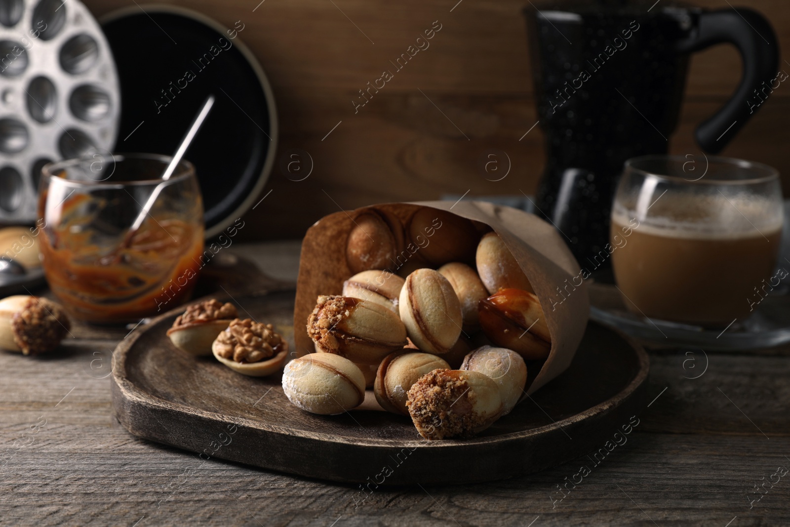 Photo of Freshly baked homemade walnut shaped cookies with condensed milk on wooden table