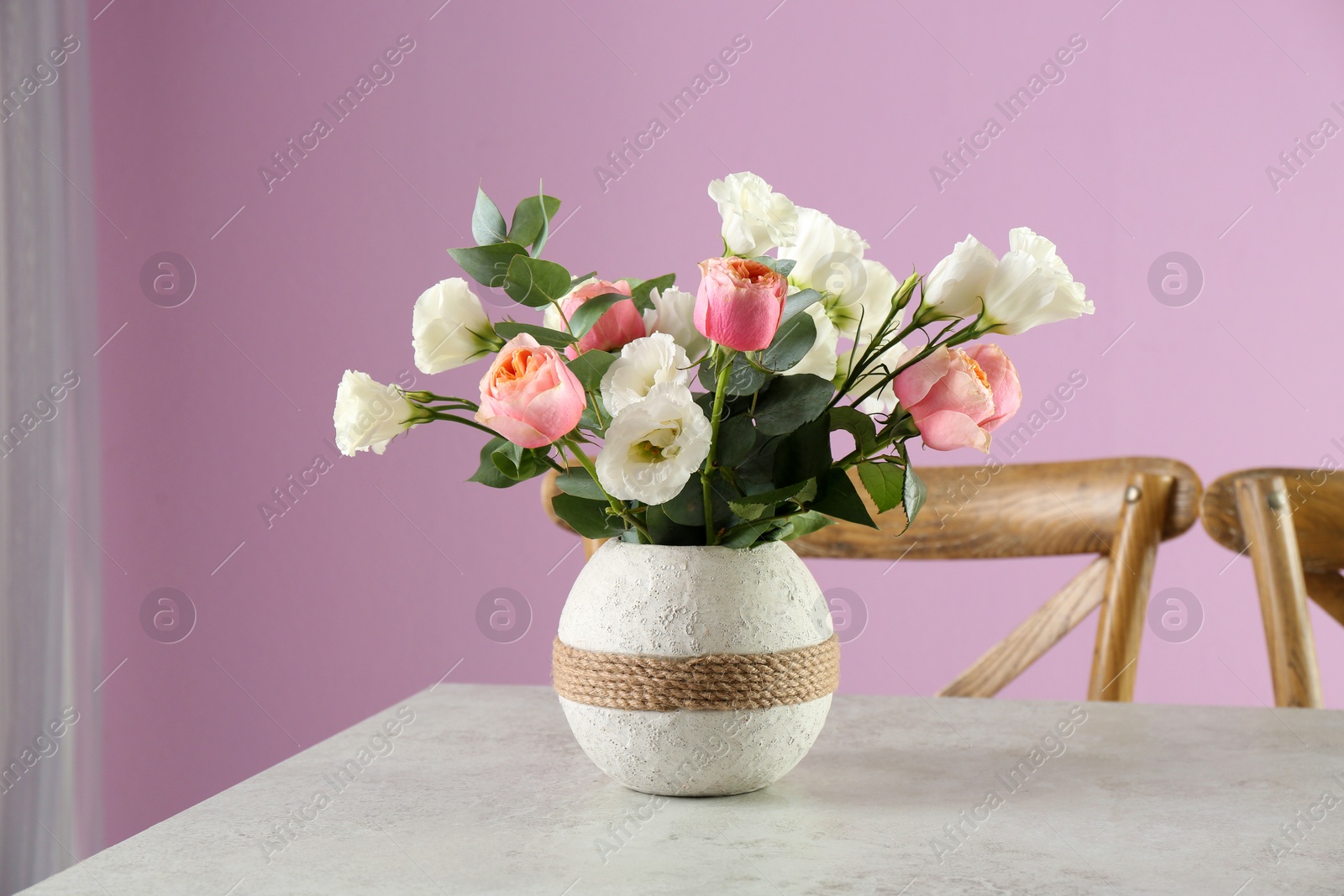 Photo of Vase with beautiful flowers as element of interior design on table in room
