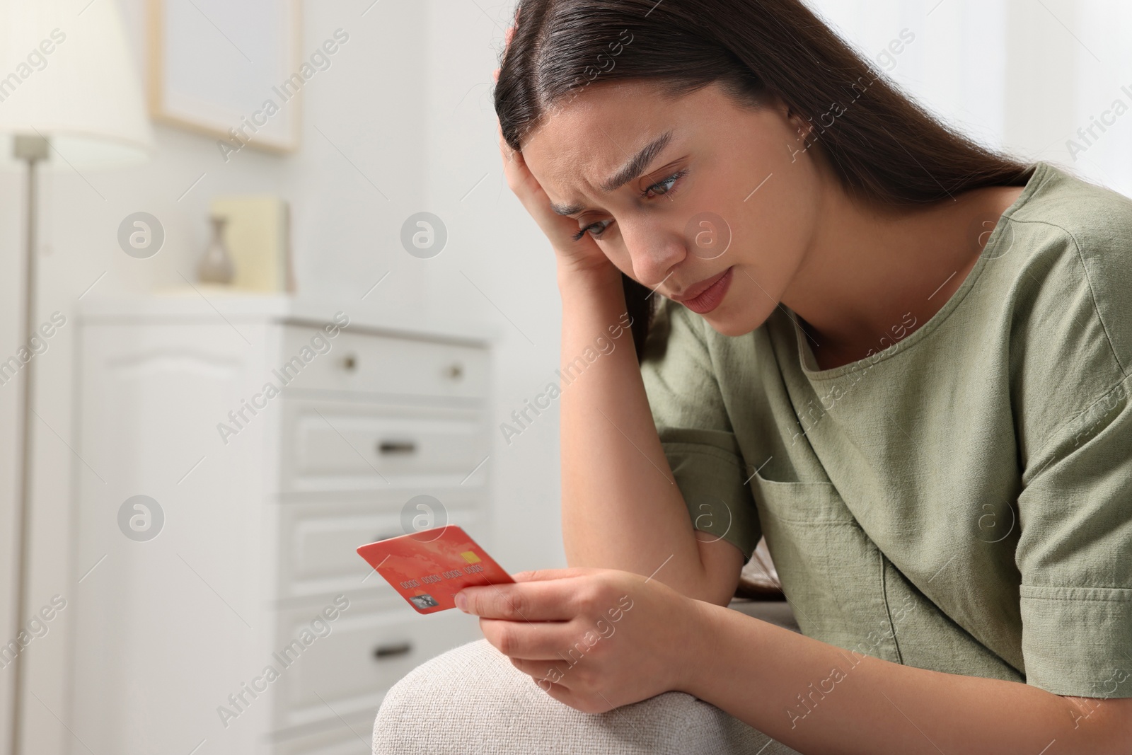 Photo of Confused woman with credit card at home. Be careful - fraud