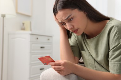 Photo of Confused woman with credit card at home. Be careful - fraud