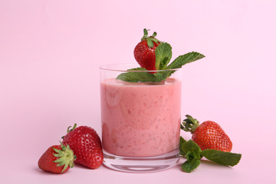 Photo of Tasty strawberry smoothie with mint in glass on pink background