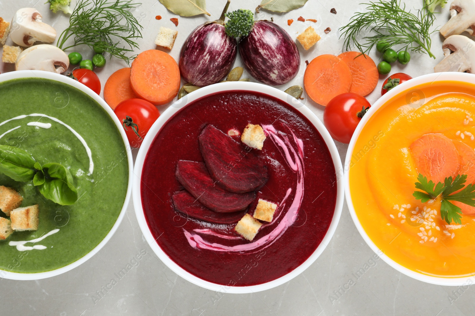 Photo of Various cream soups and ingredients on grey background, flat lay. Healthy food