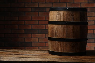Photo of Wooden barrel on table near brick wall, space for text