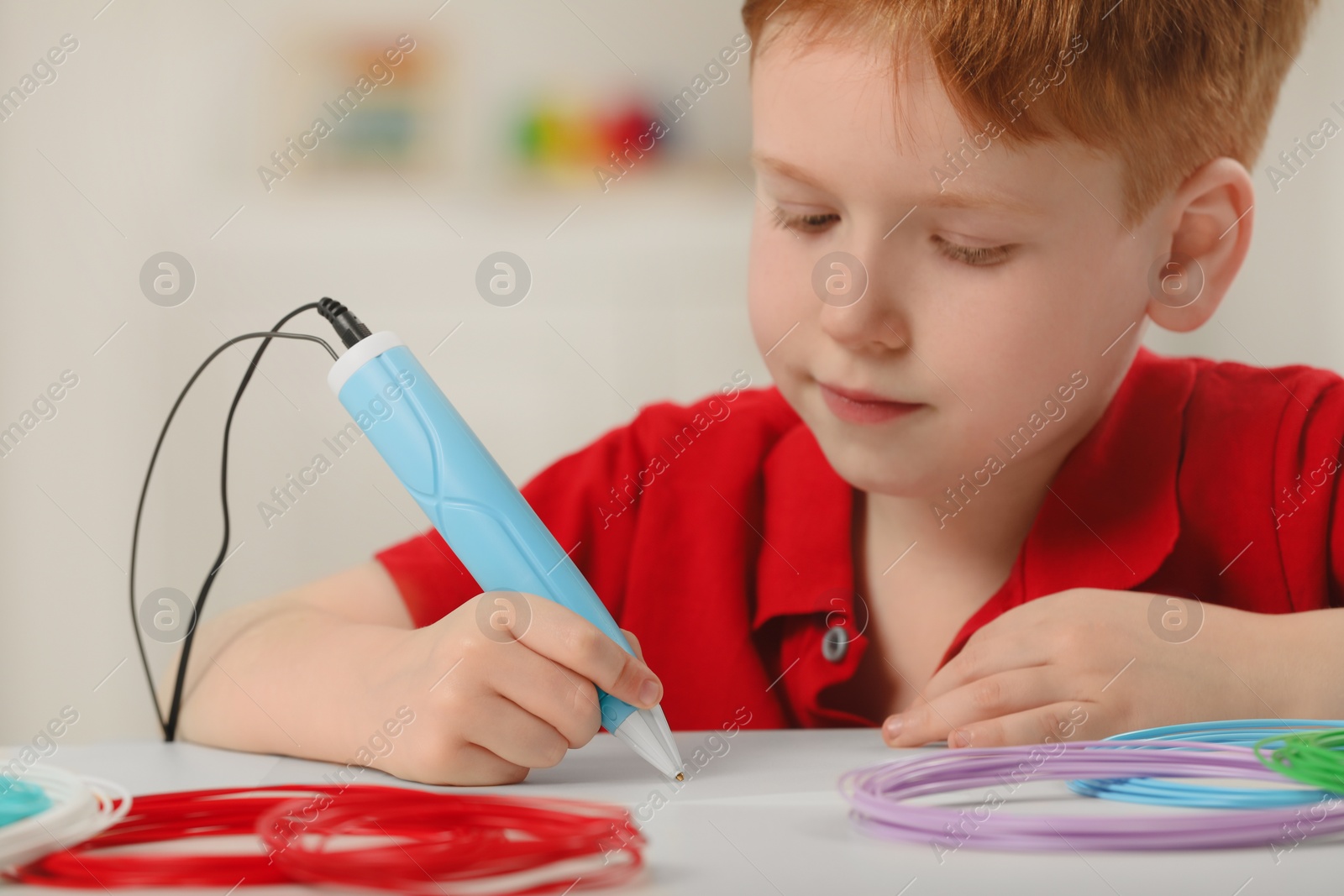 Photo of Boy drawing with stylish 3D pen at white table