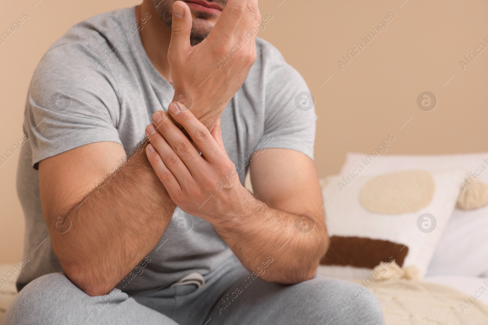 Photo of Man suffering from pain in his hand on bed indoors, closeup